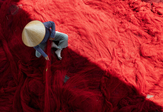 Aerial view of a person wearing a conical hat working on a sea of vibrant red threads under the sun, Thuan An, B&igrave;nh Duong, Vietnam.
