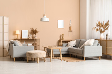 Interior of stylish living room with grey sofas, wooden table and pampas grass