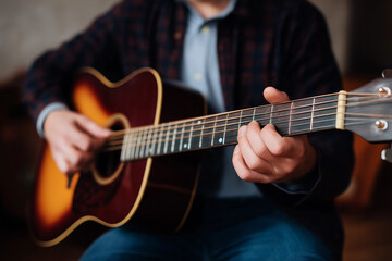 Obraz premium A musician’s hands skillfully strumming an acoustic guitar, capturing the intimate connection between the artist and their instrument, conveying emotion through music.