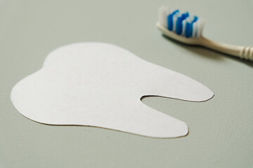 Paper tooth next to a toothbrush on a blue background, selective focus, copy space.