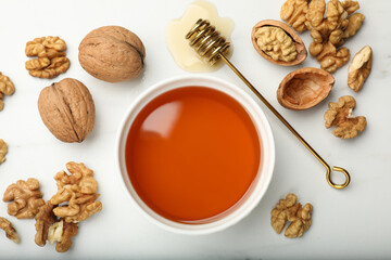 Sweet honey with walnuts and dipper on white table, flat lay