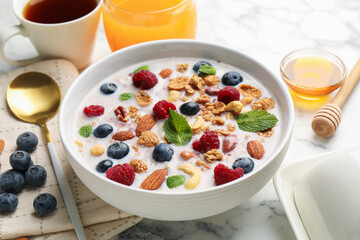 Healthy breakfast. Oatmeal with nuts, berries and milk in bowl on white marble table, closeup