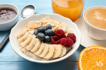 Healthy breakfast. Oatmeal with nuts, banana, berries, jam, coffee and juice on light blue wooden table, closeup