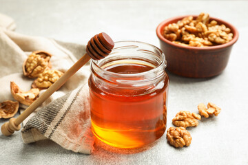 Honey in jar, walnuts and dipper on light table, closeup