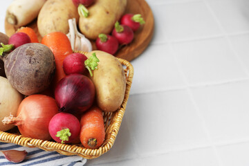 Different raw vegetables on white tiled table, closeup. Space for text