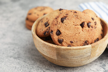 Delicious chocolate chip cookies in bowl on gray textured table, closeup