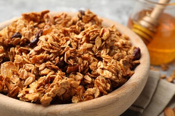 Tasty granola with dried fruits and honey on light grey table, closeup