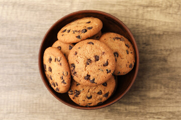 Obraz premium Delicious chocolate chip cookies in bowl on wooden table, top view