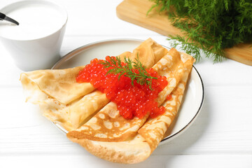Tasty crepes with red caviar, sour cream and dill on table, closeup