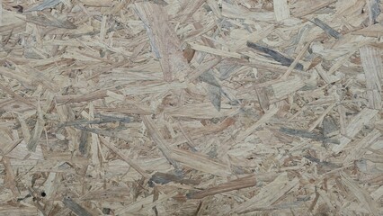 A light brown OSB (Oriented Strand Board) wood texture, showing natural wood grain and chips compressed together. Ideal for design backgrounds and building materials.