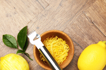 Lemon zest, fresh fruits and zester tool on wooden table, flat lay