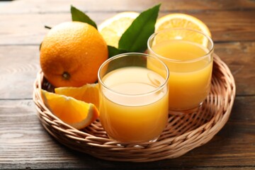 Fresh orange juice, fruits and green leaves on wooden table, closeup