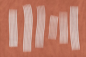 Stripes in white on a textured orange background show design elements created by drawing tools on paper