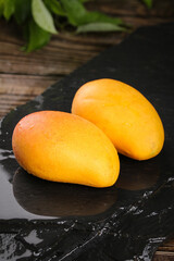 Fresh Hainan Mangoes on Dark Slate with Rustic Wood Background