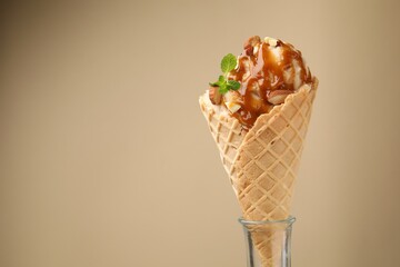 Tasty ice cream with caramel sauce, almonds and mint on beige background. Space for text