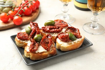 Delicious bruschettas with cream cheese, sun-dried tomatoes and green olives on gray table, closeup