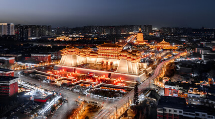 Illuminated Chinese Palace Complex with Golden Lighting and Modern City Skyline at Dusk © DoThi