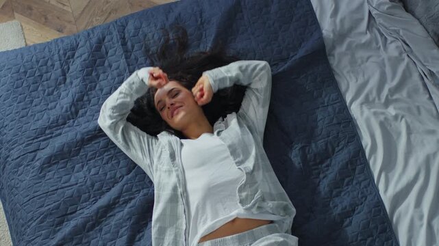 Top view from above falling Caucasian female girl woman fall on cozy comfortable bed in home bedroom relaxing joyful smiling lady smile resting pleasure domestic weekend enjoying lying on new mattress
