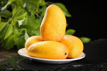 Fresh Golden Mangoes on White Plate with Green Leaves