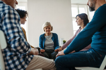 Obraz premium Group of people sitting in a circle and sharing experiences during guided therapeutic session.