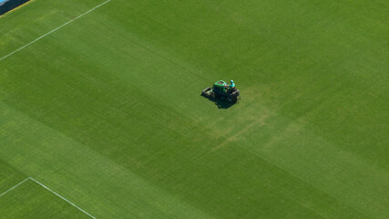 Aerial closeup view of a gardener working on a soccer field with a lawnmower. © Stefano Tammaro