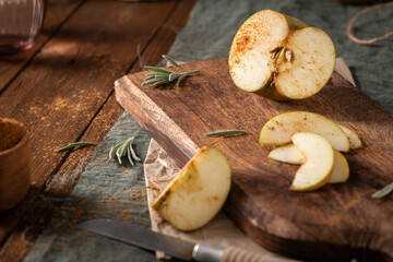 A sliced Reinette apple and its wedges, dusted with cinnamon, are shown on a rustic wooden board.