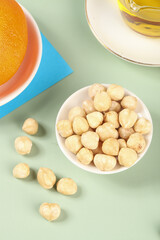 Roasted Hazelnut Kernels with Oil and Citrus on Mint Green Background