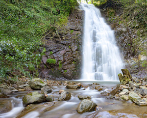 Stunning mountain waterfall captured with long exposure, creating smooth flowing water and highlighting natural textures, rocks, and surrounding greenery. Perfect for nature, landscape, or travel proj