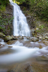 Obraz premium Stunning mountain waterfall captured with long exposure, creating smooth flowing water and highlighting natural textures, rocks, and surrounding greenery. Perfect for nature, landscape, or travel proj