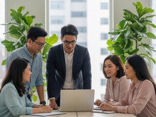 Diverse group of business colleagues collaborating on a laptop in an office