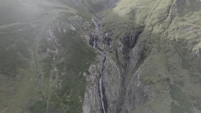 Aerial view of multiple waterfalls flowing from a mountain river in a high-altitude gorge of Tusheti, Georgia