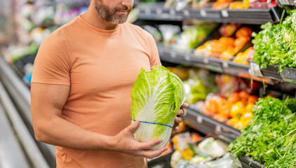 Healthy lifestyle. Fresh food store. Man in grocery store. Man shopping in vegetable supermarket. Grocery consumer with Napa cabbage. Man shopping Napa cabbage in grocery store. Groceries and produce