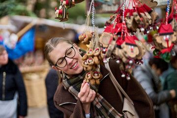 Cheerful young woman looking for New Year decorations in traditional street market