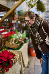 Cheerful young woman looking for New Year decorations in traditional street market
