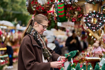 Cheerful young woman looking for New Year decorations in traditional street market
