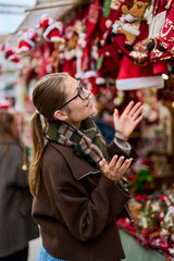 Cheerful young woman looking for New Year decorations in traditional street market