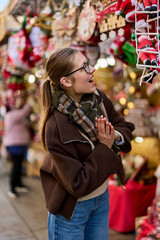 Cheerful young woman looking for New Year decorations in traditional street market