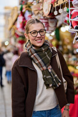 Cheerful young woman looking for New Year decorations in traditional street market