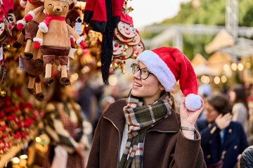 Cheerful young woman looking for New Year decorations in traditional street market