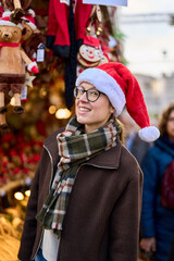 Cheerful young woman looking for New Year decorations in traditional street market