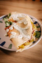 Close-up of savory crepes filled with minced meat, pickles and creamy herb sauce. Rustic homemade comfort food with soft natural ligh