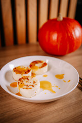 Cheese pancakes with fruit sauce served on white plate. Cozy autumn breakfast with pumpkin and warm minimal composition