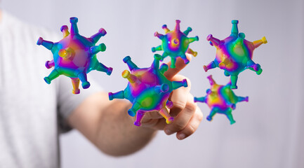 Abstract digitally generated illustration of colourful virus cells interacting with a human hand, representing