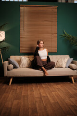 Obraz premium Young woman relaxing on sofa in modern living room