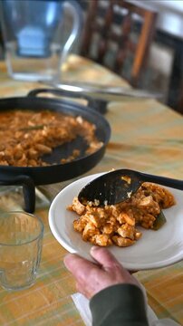 Vertical view of hands serving paella ready to eat at a family meal at home, homemade and traditional food, recipes for Valencian paellas and soupy rice dishes, 