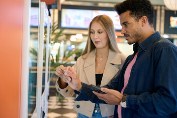 Couple using touch screen kiosk for ordering food