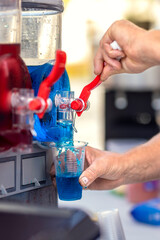 Filling plastic cup with colorful sirup crushed fruit ice. Frozen mixed blue and red refreshing summer drink. Refreshing Granitas