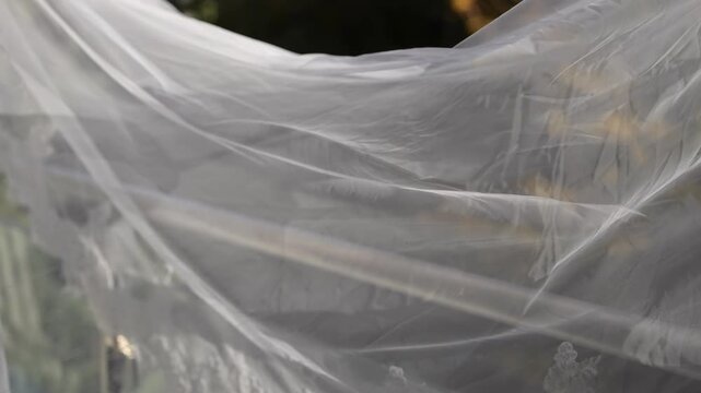 Flowing Wedding Veil Outdoors In Breeze, Translucent Tulle Drifts Across Sunlit Garden, Soft Highlights And Gentle Folds Create Romantic