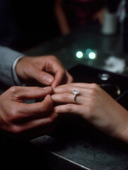 Couple exchanges ring at a romantic proposal in a dim setting