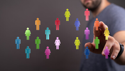 A man's hand selecting from a collection of colorful virtual people icons, representing concepts like diversity, connection, and teamwork. Ideal